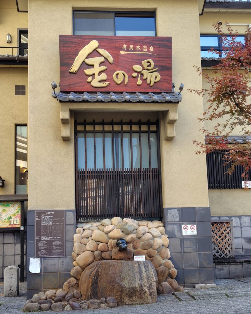 有馬温泉「金の湯」の外観。入口前のモニュメントと建物全体の様子。
